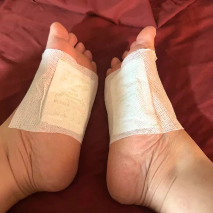 Pair of feet wearing Xuhaha cleansing foot pads secured with white adhesive sheets